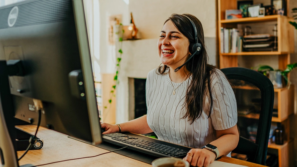 Image from the cover of the Vocus Whitepaper: Transforming the employee experience. Image of a girl with a headset on working from home at desktop.