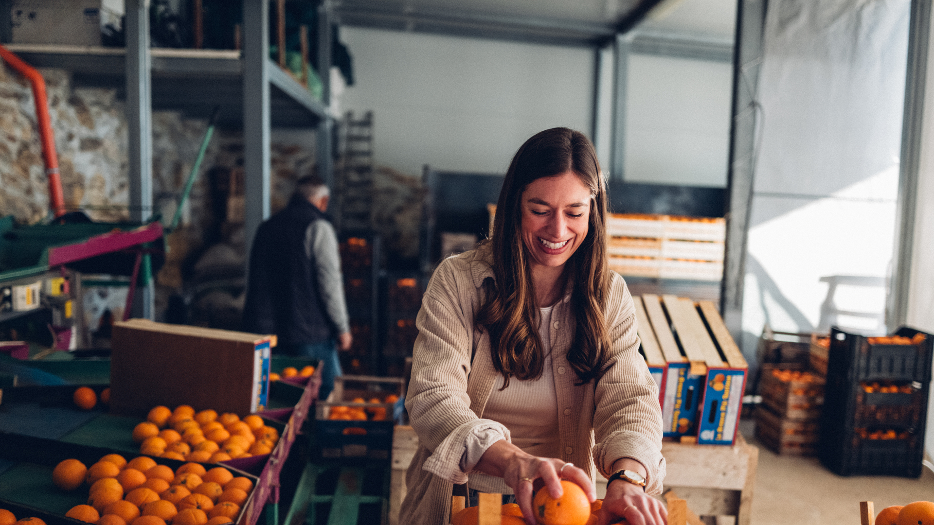 Woman filling boxes of oranges in warehouse