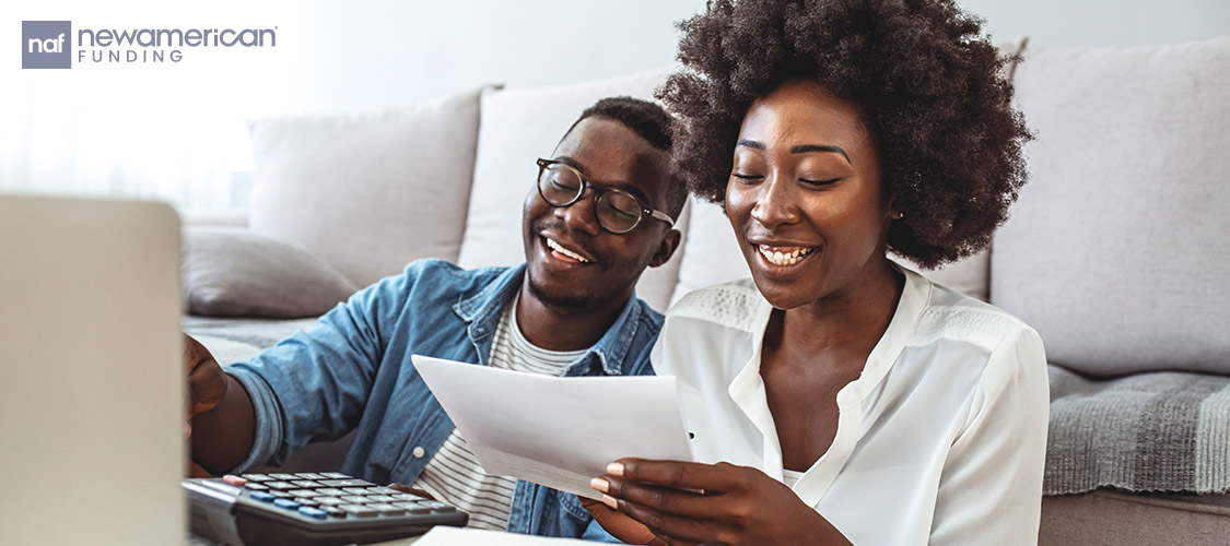 A happy Black couple looks over their financial notes