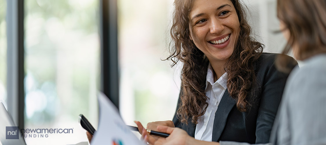 A smiling white woman looks over paperwork