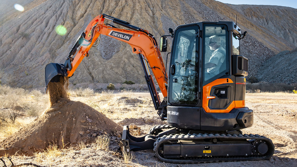 A DEVELON mini excavator digging dirt on a job site.