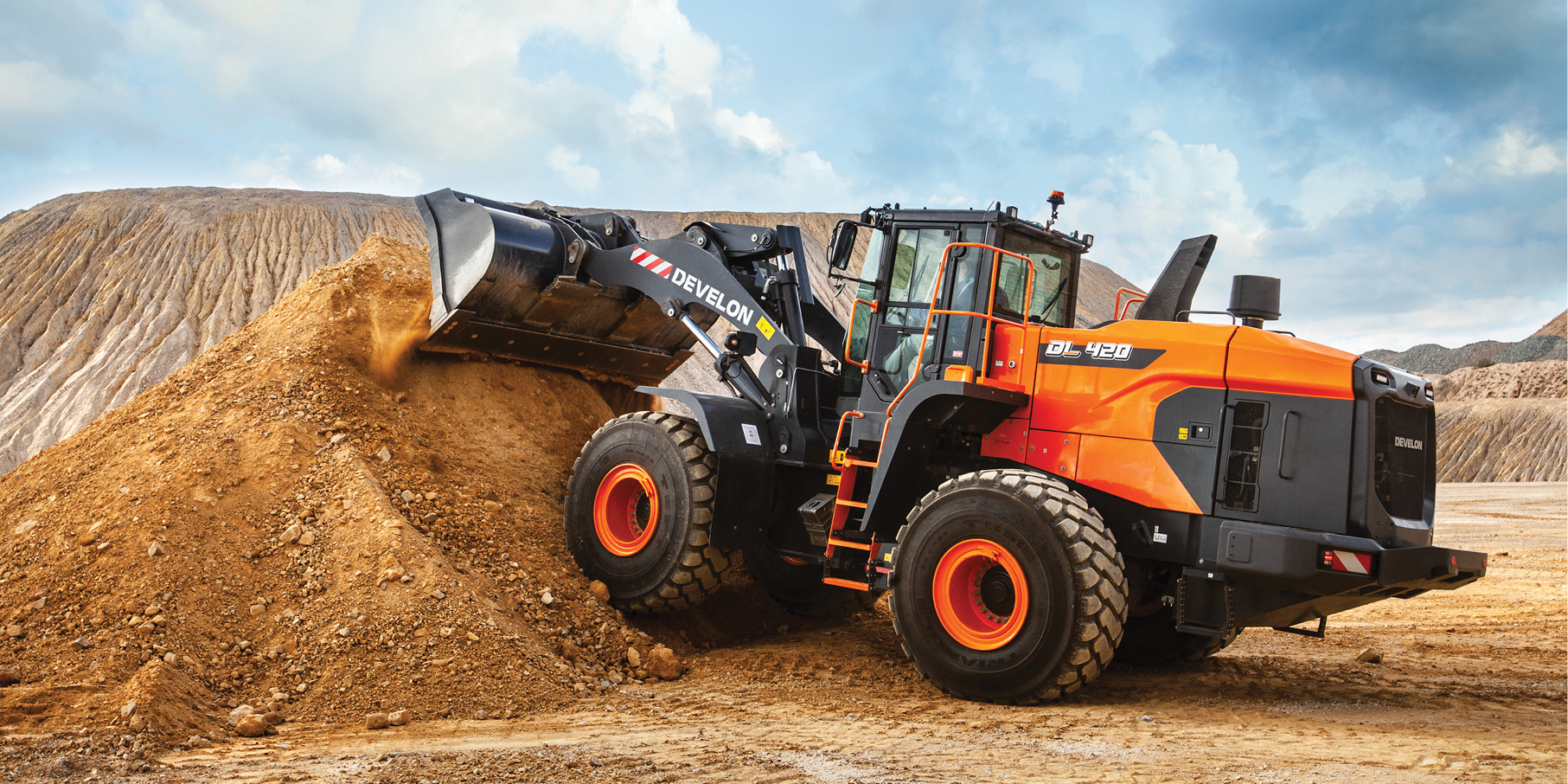 A DEVELON wheel loader pushing a pile of dirt on a job site.