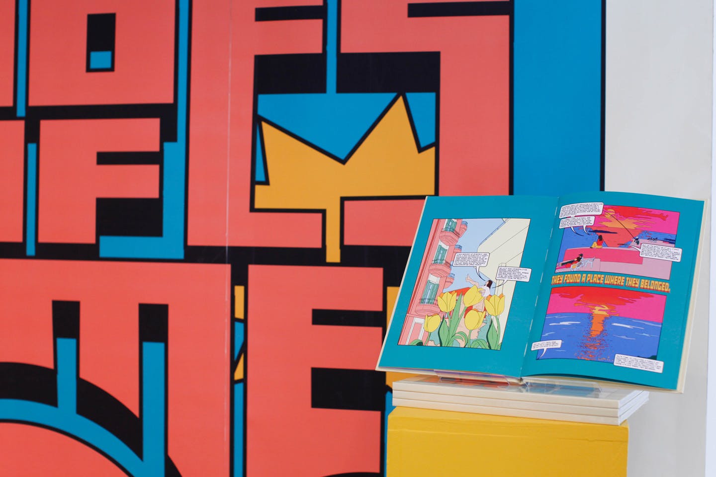 Open comic book with colorful panels against bold graphic wall art