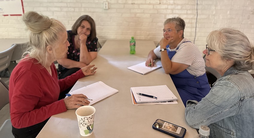 Four women seated at a table having an engaged discussion