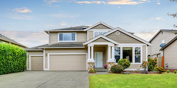 A nice beige house in a neighborhood sitting on a well-maintained small green lawn
