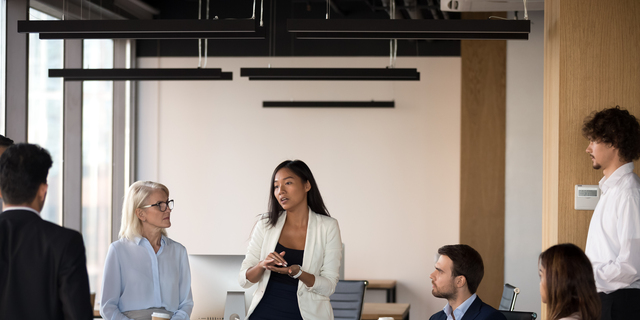 Serious asian coach speaking at diverse corporate group meeting