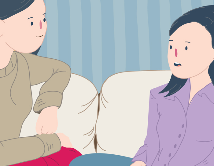 Mother and daughter sitting on couch talking