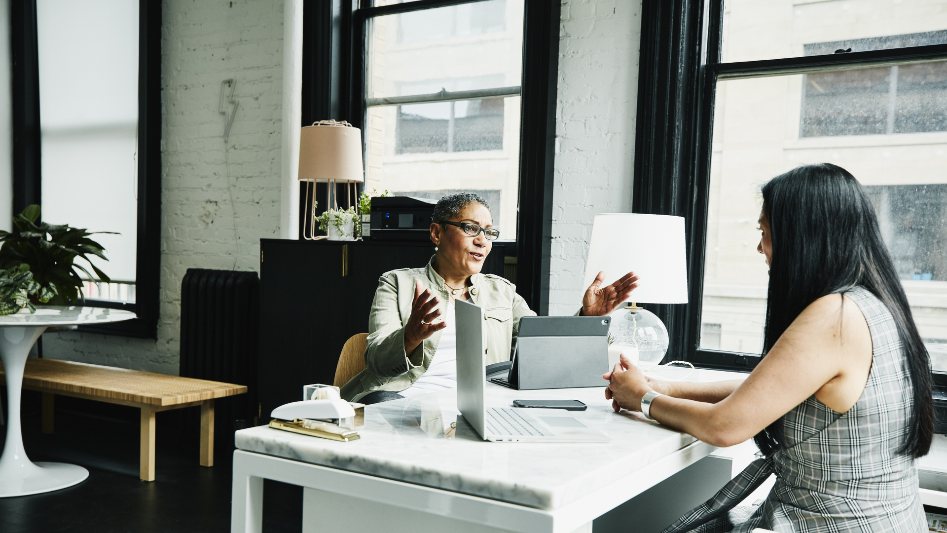 Female financial advisor in discussion with mature female business owner at desk in office