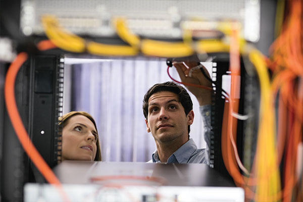 Technicians inspecting ethernet cables in a server rack
