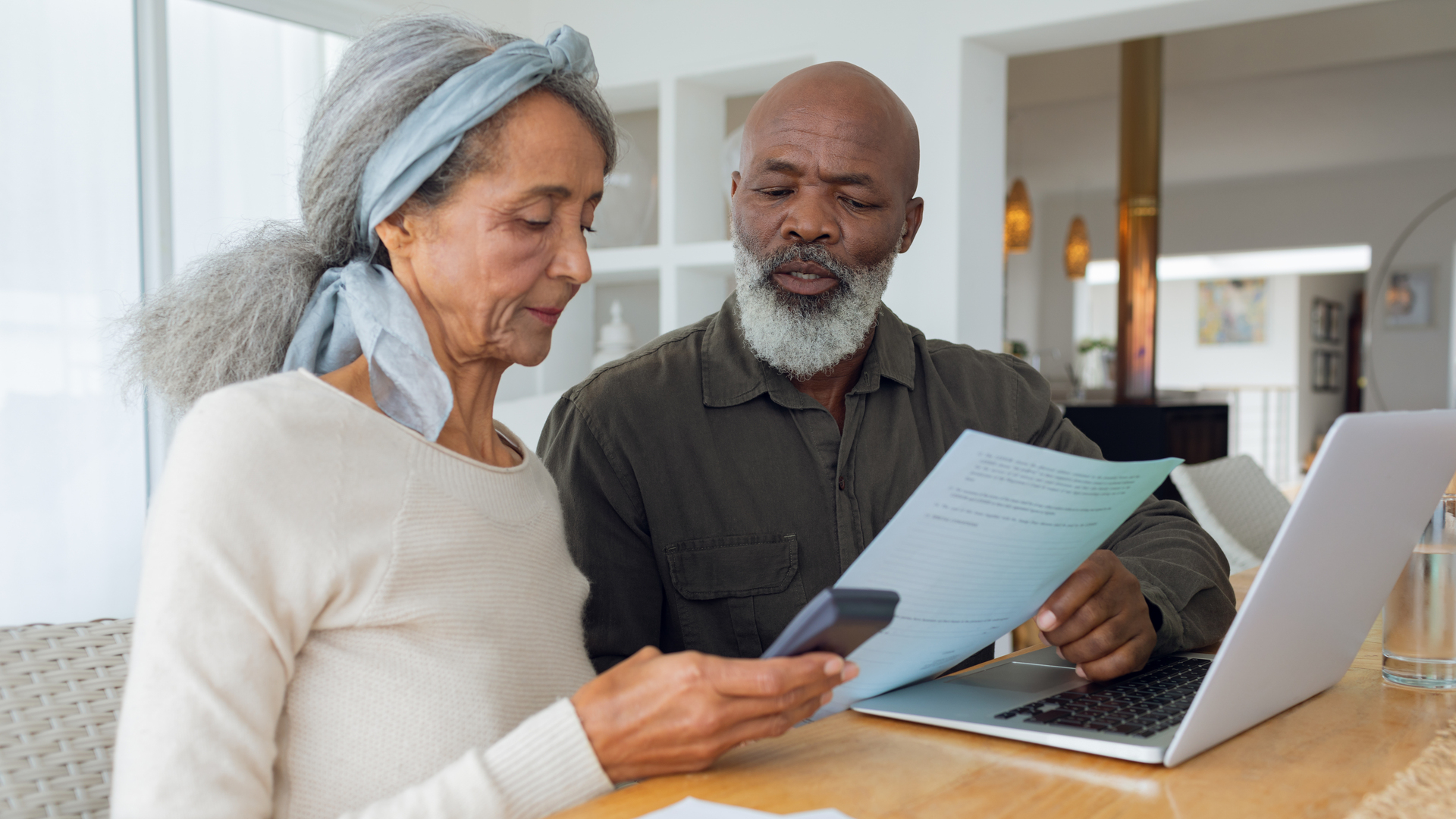 Couple discussing papers and using laptop inside a room