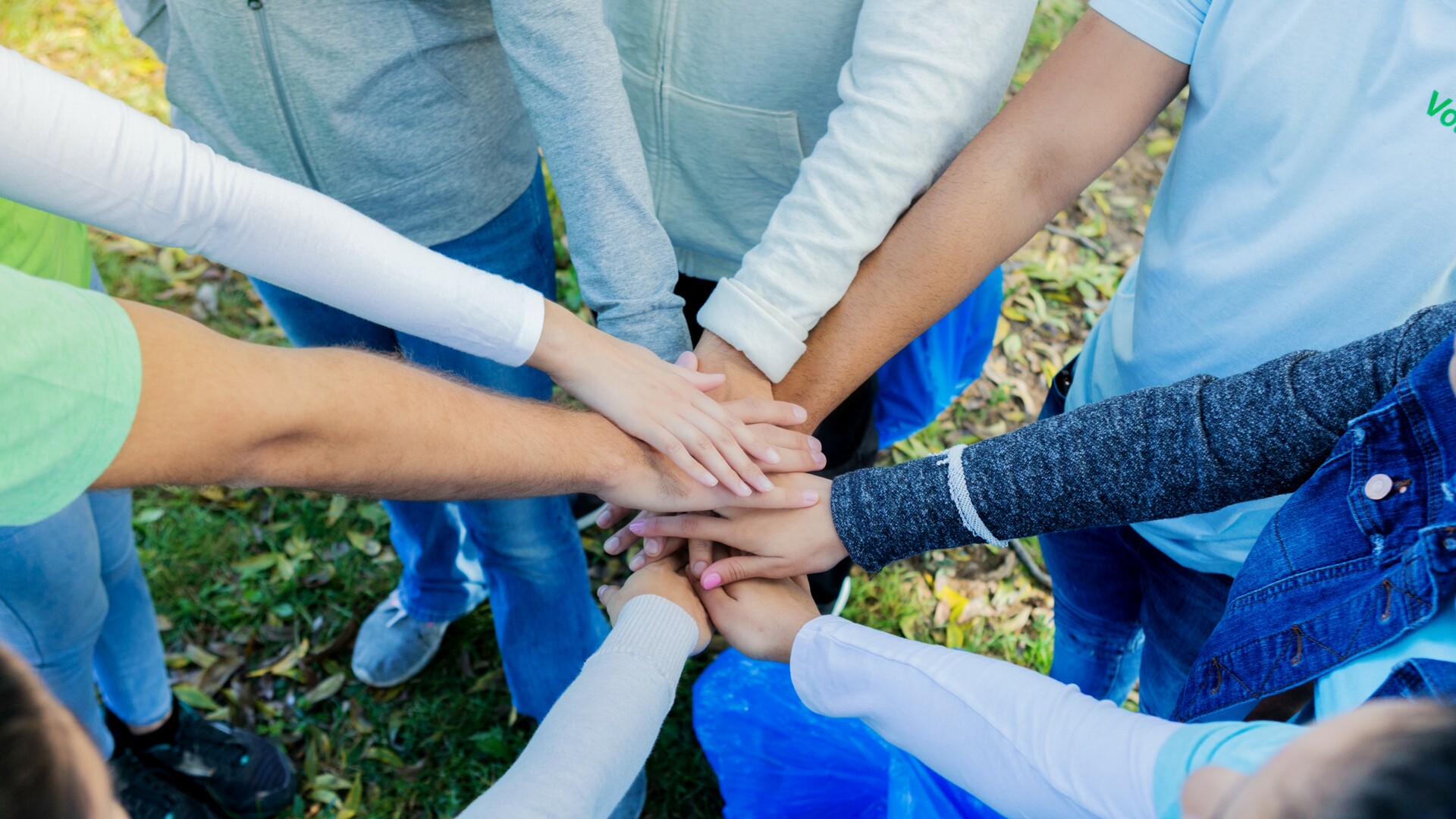 Group of unrecognizable volunteers stack hands before serving
