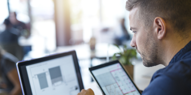 Business man looking and analyzing projects on his laptop computer and tablet.