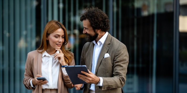 Business people using digital tablet and smartphone outdoors