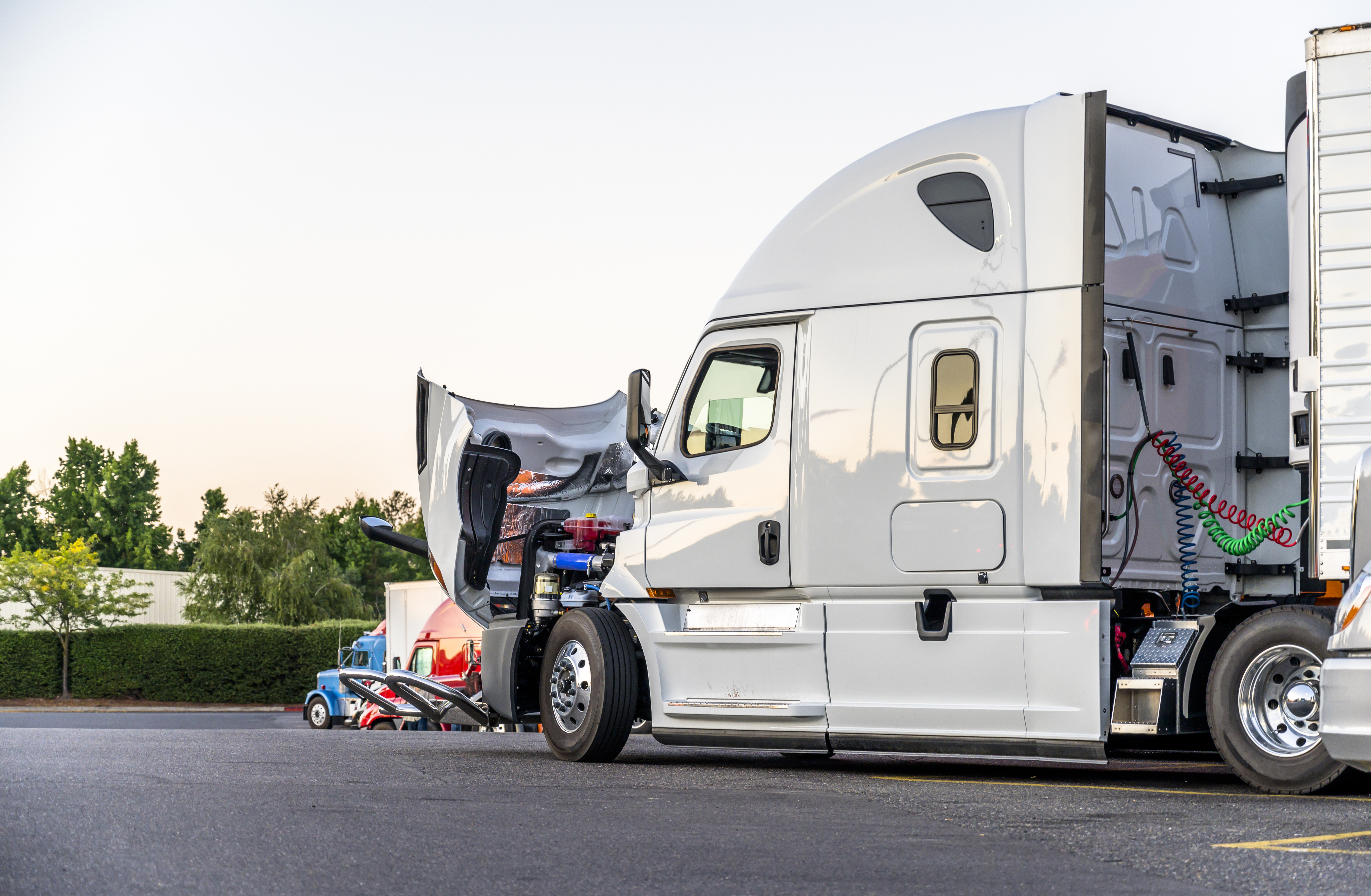 A field service technician performs a heavy equipment repair under the hood of a semi truck.