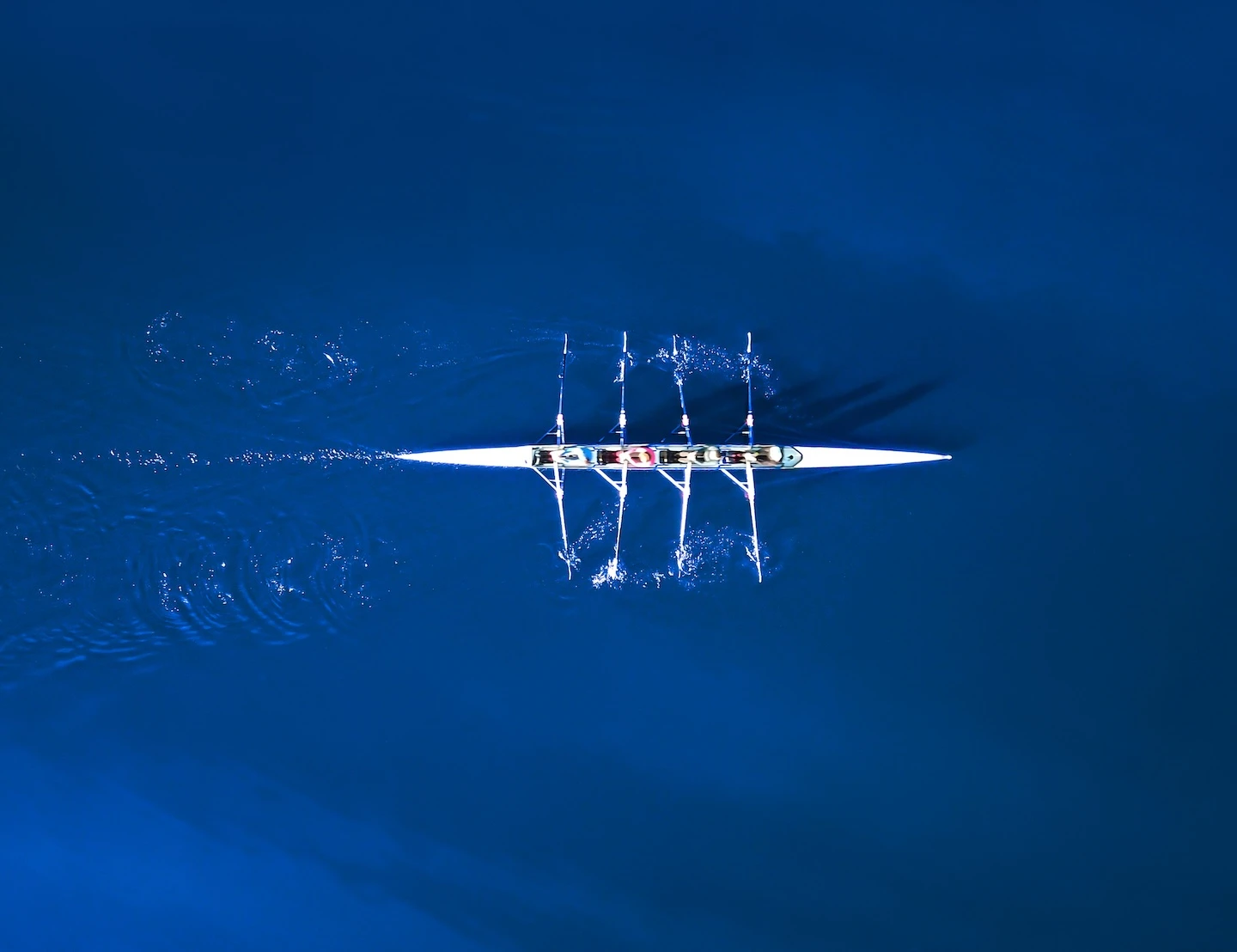 Four people kayaking in a large body of clear blue water