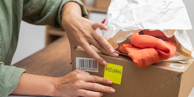 woman online shopper affixes a barcode sticker to a cardboard box, marking it for return and refund.
