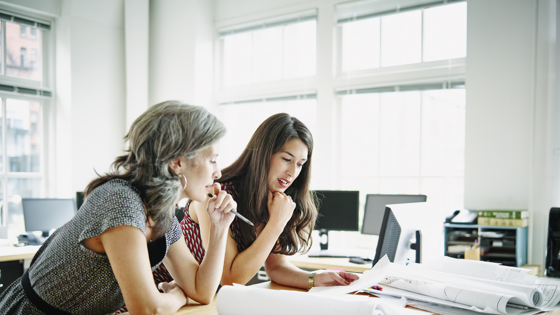 Businesswomen leaning on table discussing plans