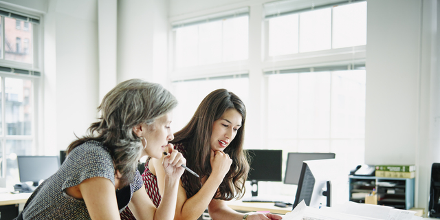 Businesswomen leaning on table discussing plans