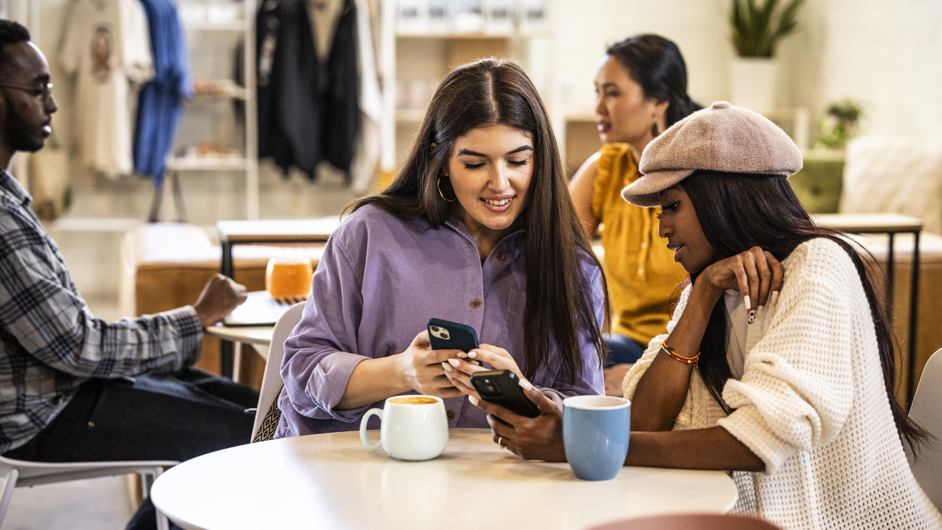 Young women exchanging information with smartphones in modern coffeeshop