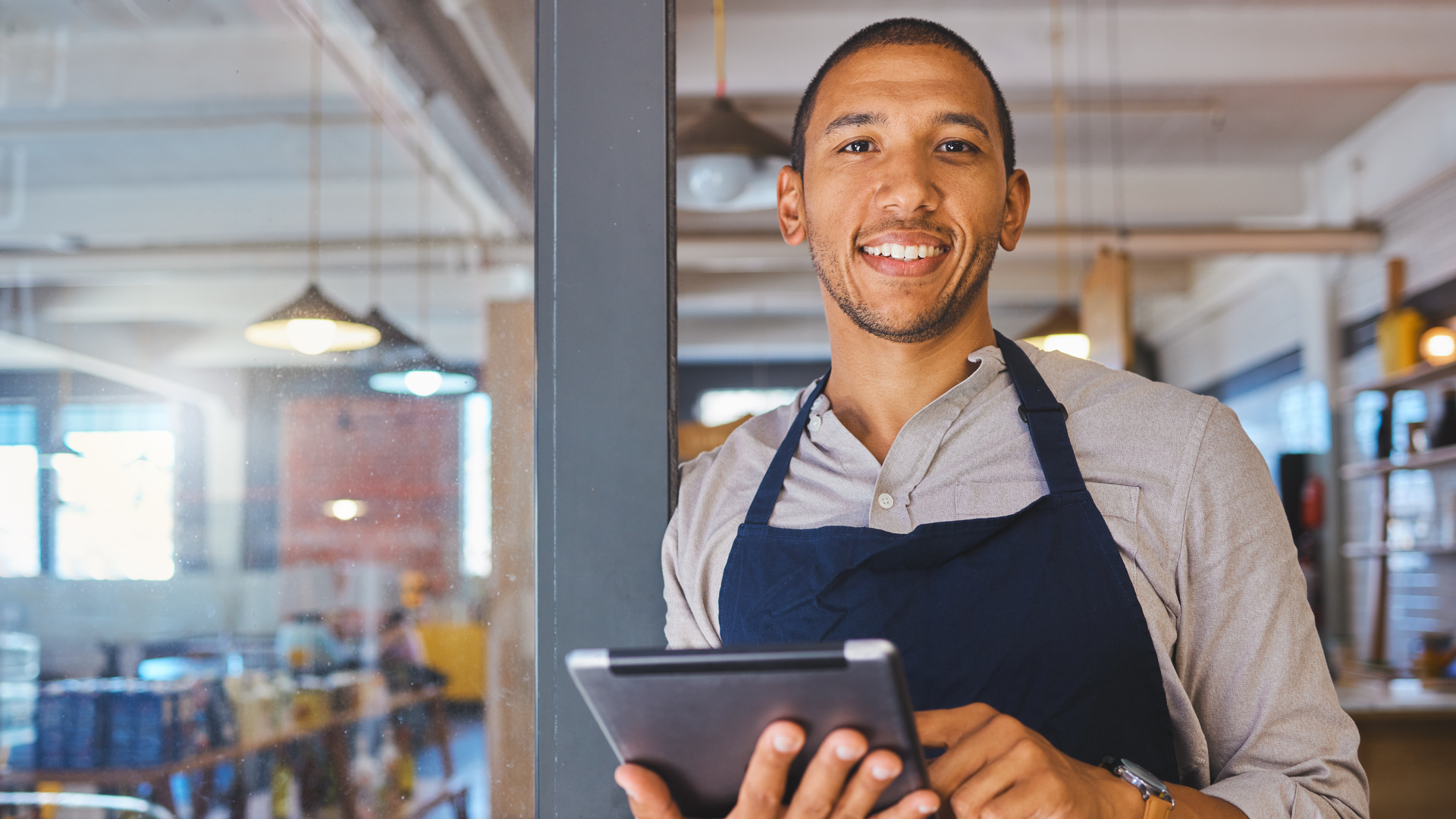 Restaurant entrepreneur with tablet, leaning on door and open to customers portrait. Owner, manager or employee of a startup fast food store, cafe or coffee shop business standing happy with a smile