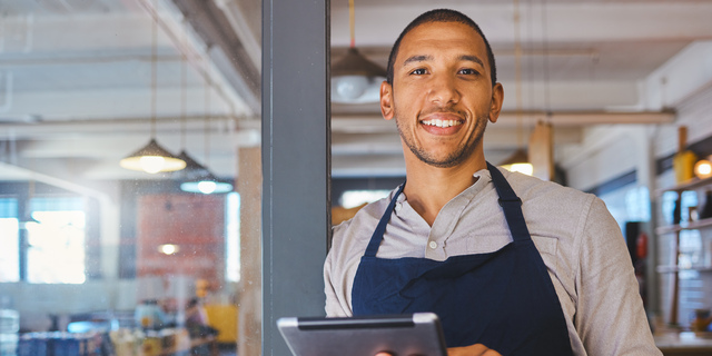 Restaurant entrepreneur with tablet, leaning on door and open to customers portrait. Owner, manager or employee of a startup fast food store, cafe or coffee shop business standing happy with a smile