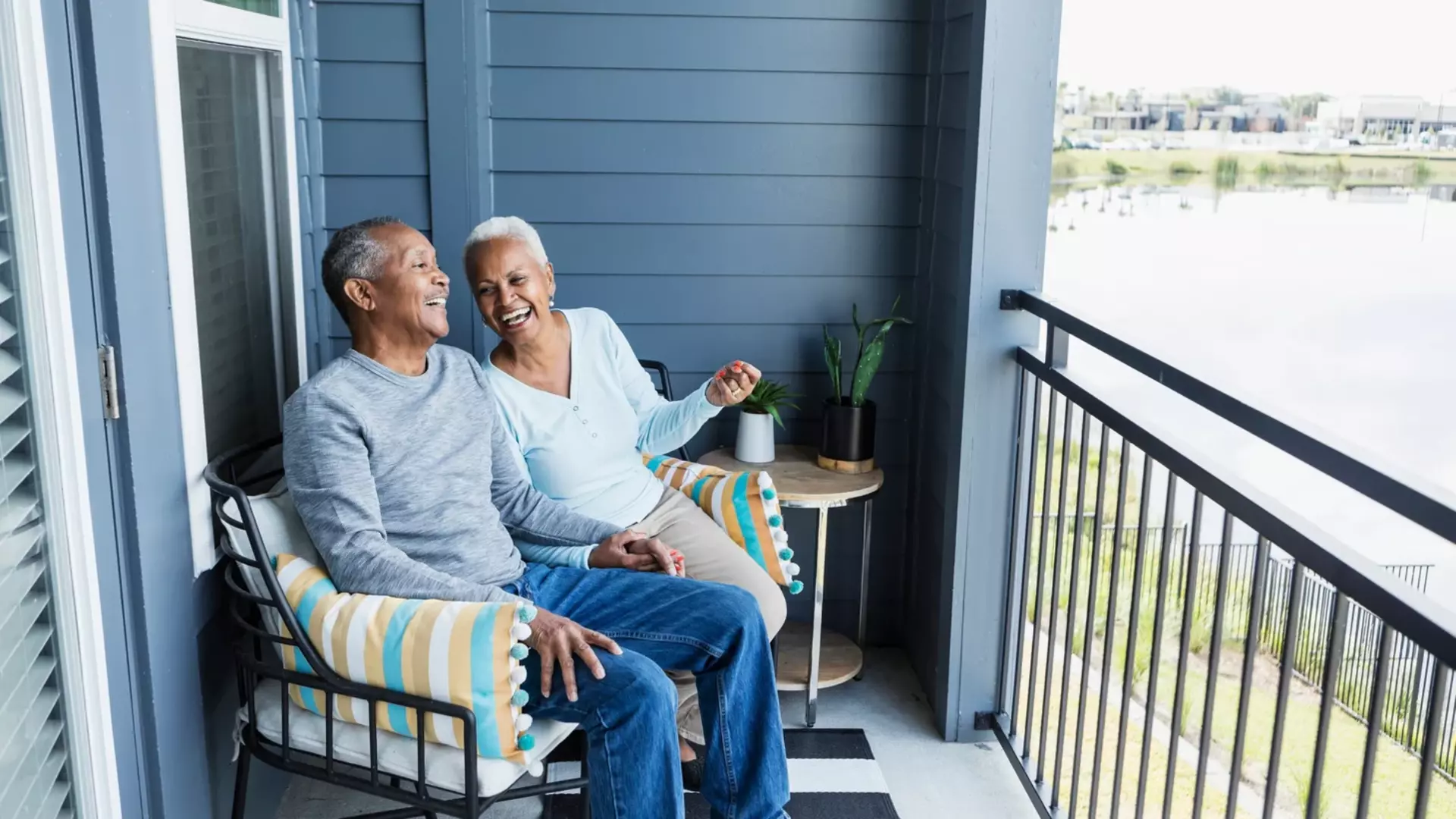 Happy_mature_couple_sitting_on_balcony_overlooking_a_pond_QtQebFf.webp