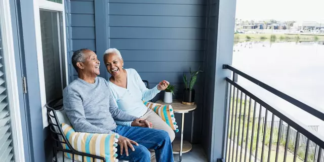 Happy_mature_couple_sitting_on_balcony_overlooking_a_pond_QtQebFf.webp