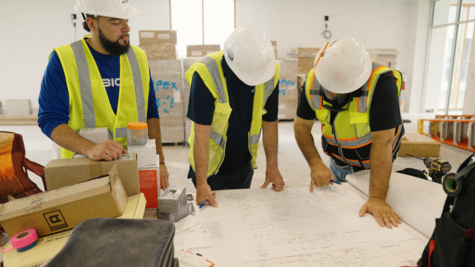 BICSI certified installation team reviewing architectural blueprints and telecommunications layout on a construction site