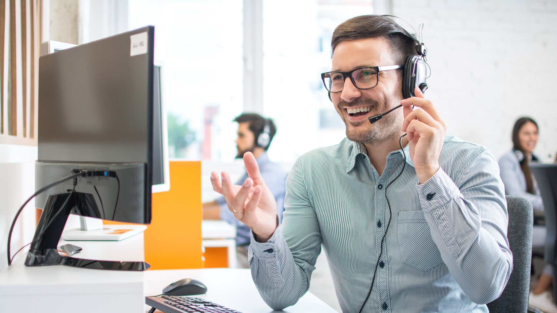 Happy handsome technical support operator with headset working in call centre