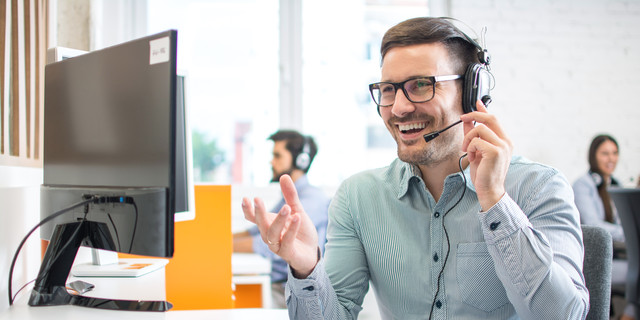 Happy handsome technical support operator with headset working in call centre