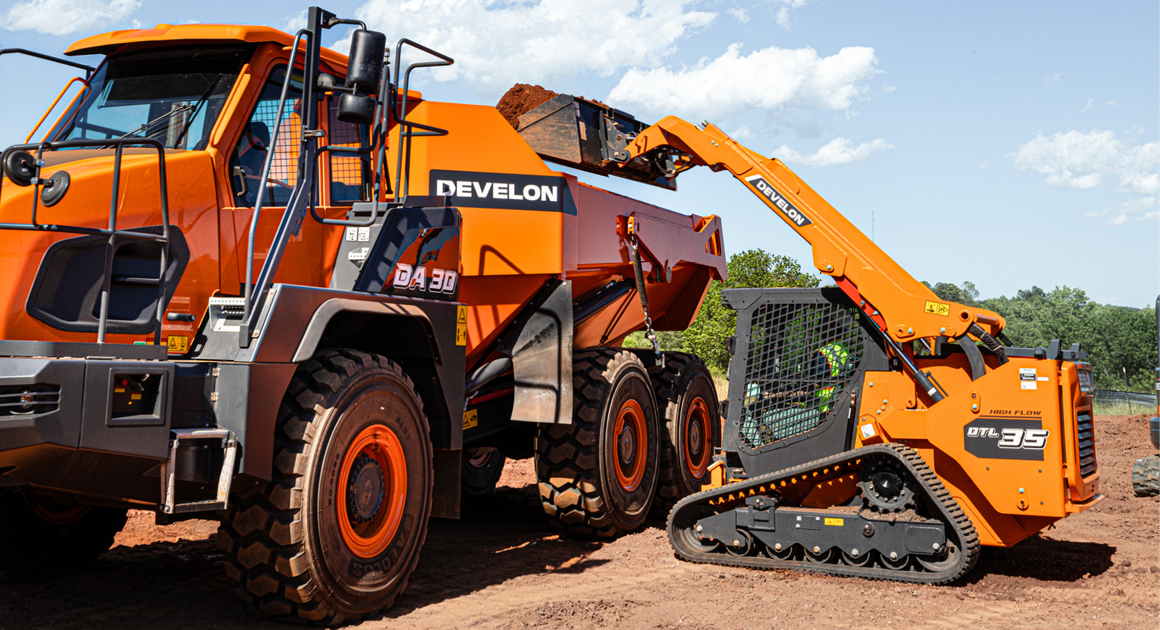 A DEVELON DTL35 compact track loader dumps dirt into a high-sided DEVELON articulated dump truck.