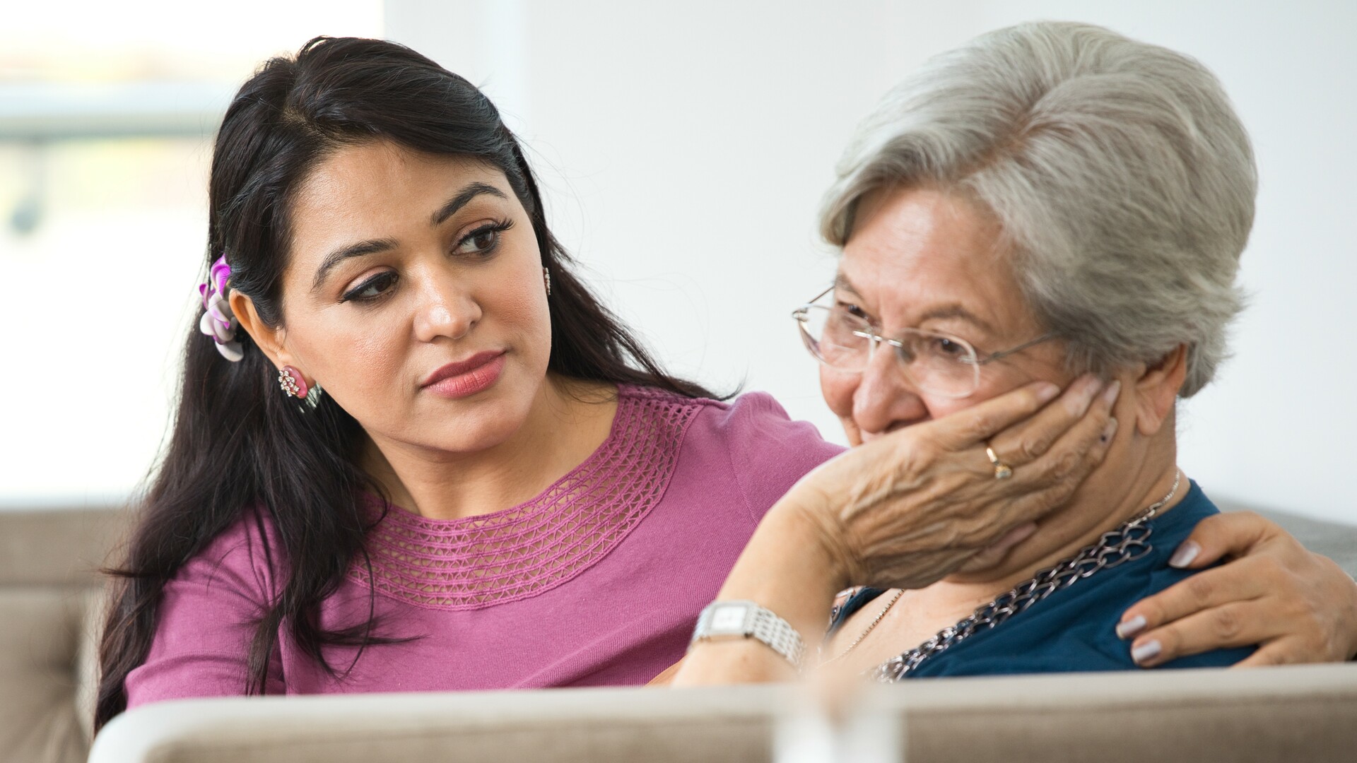 Woman consoling old mother at home