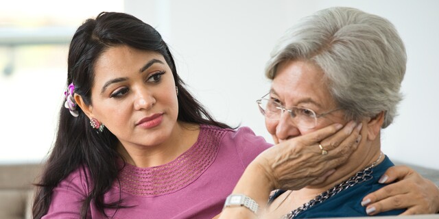 Woman consoling old mother at home