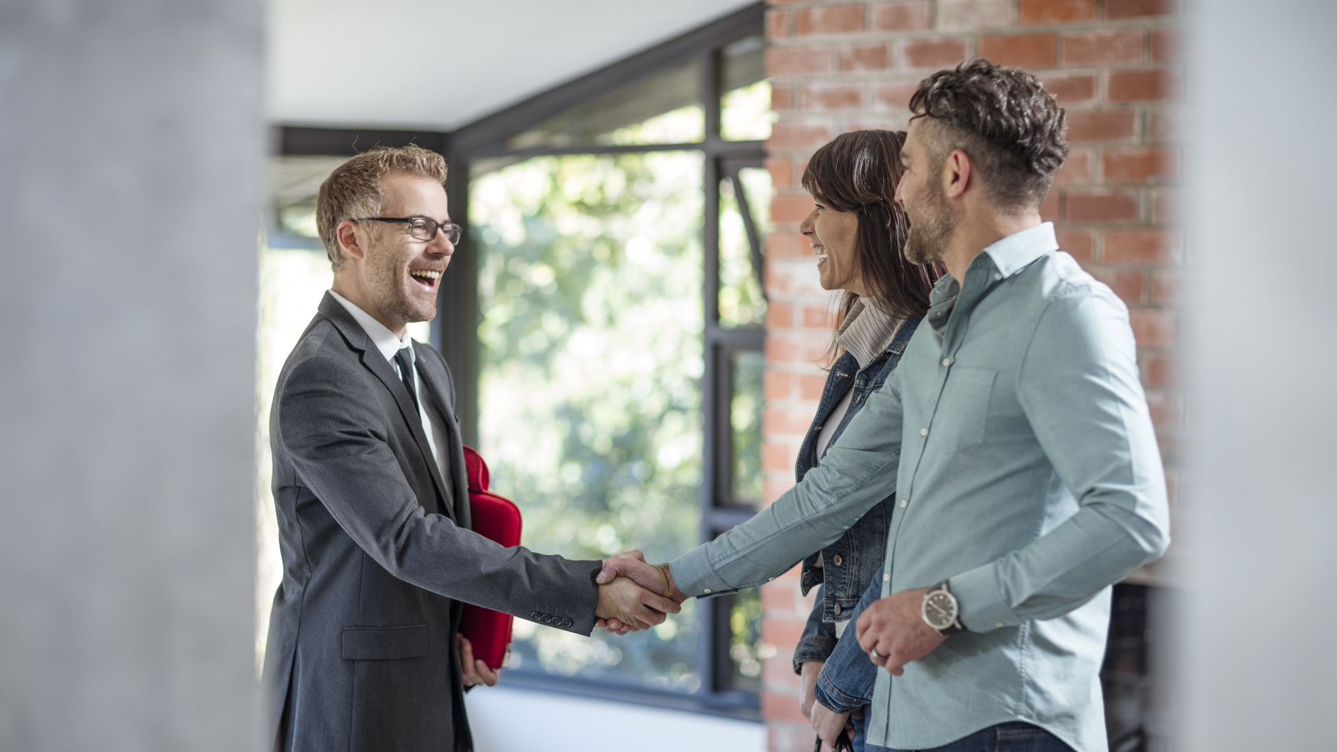 Estate agent shaking hands with couple in empty home