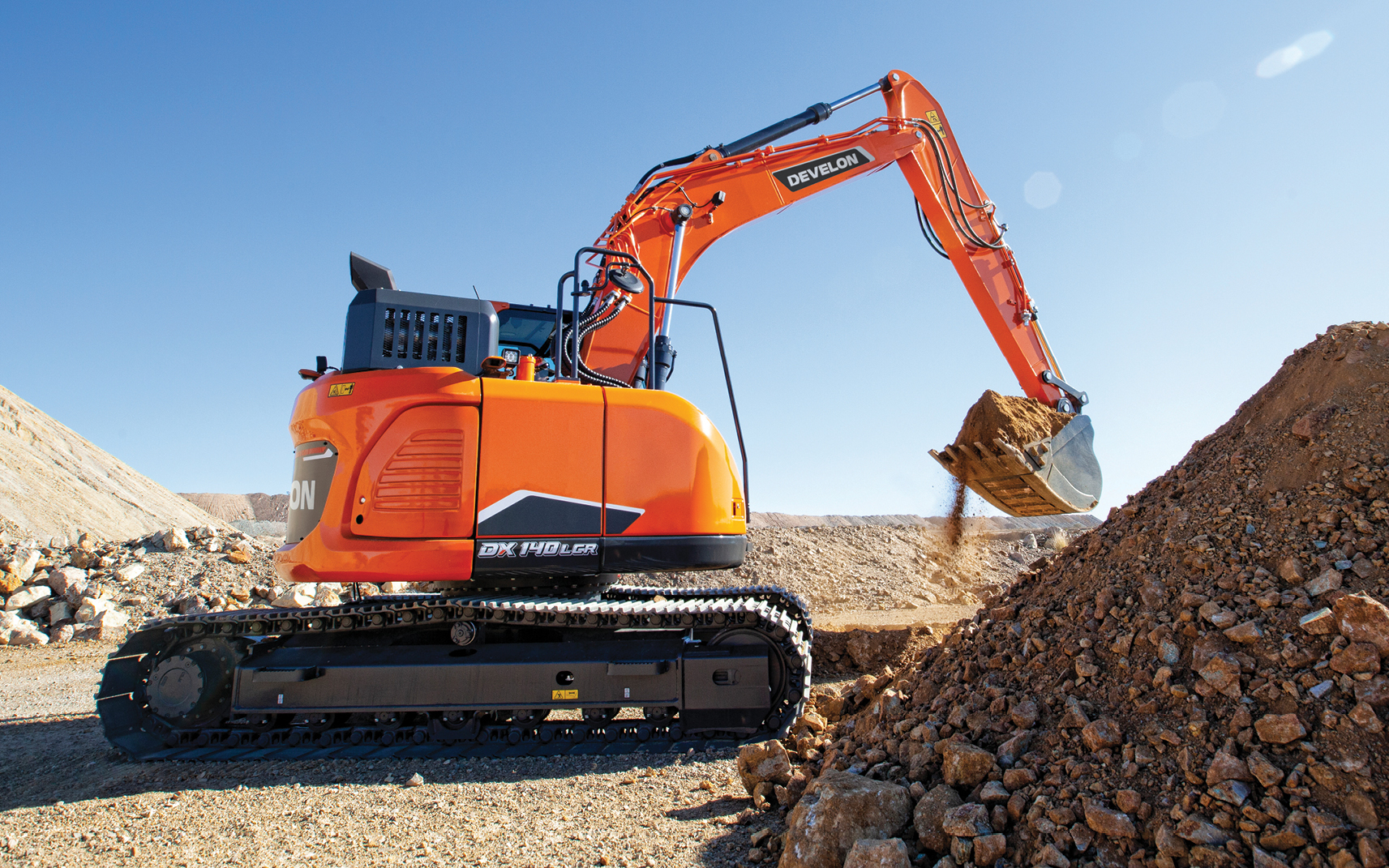 DEVELON crawler excavator moves rocks and dirt on a work site.