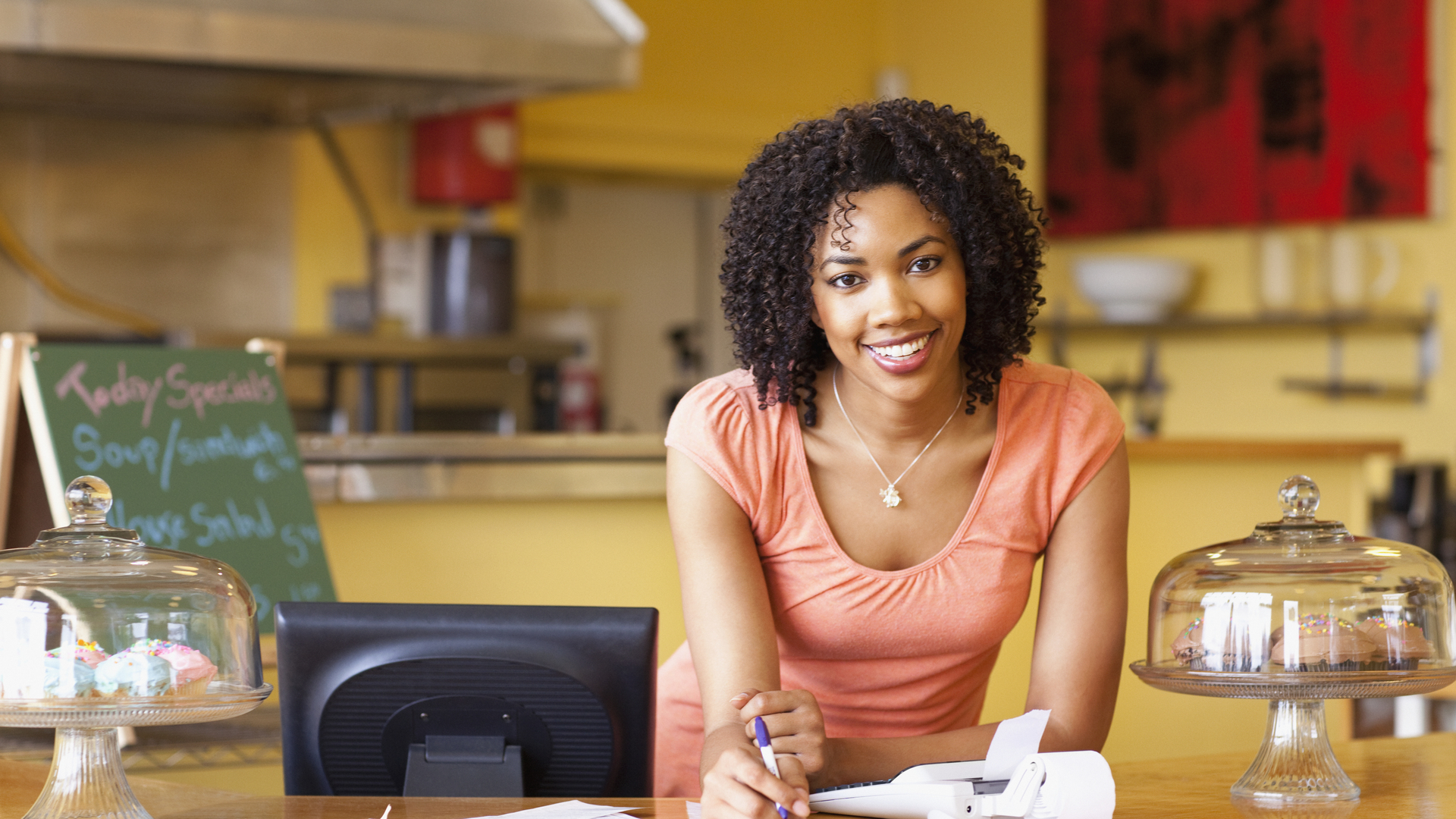 African American business owner paying bills at cafe counter