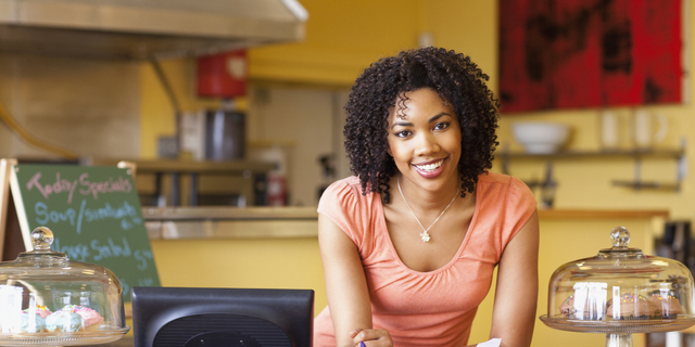 African American business owner paying bills at cafe counter