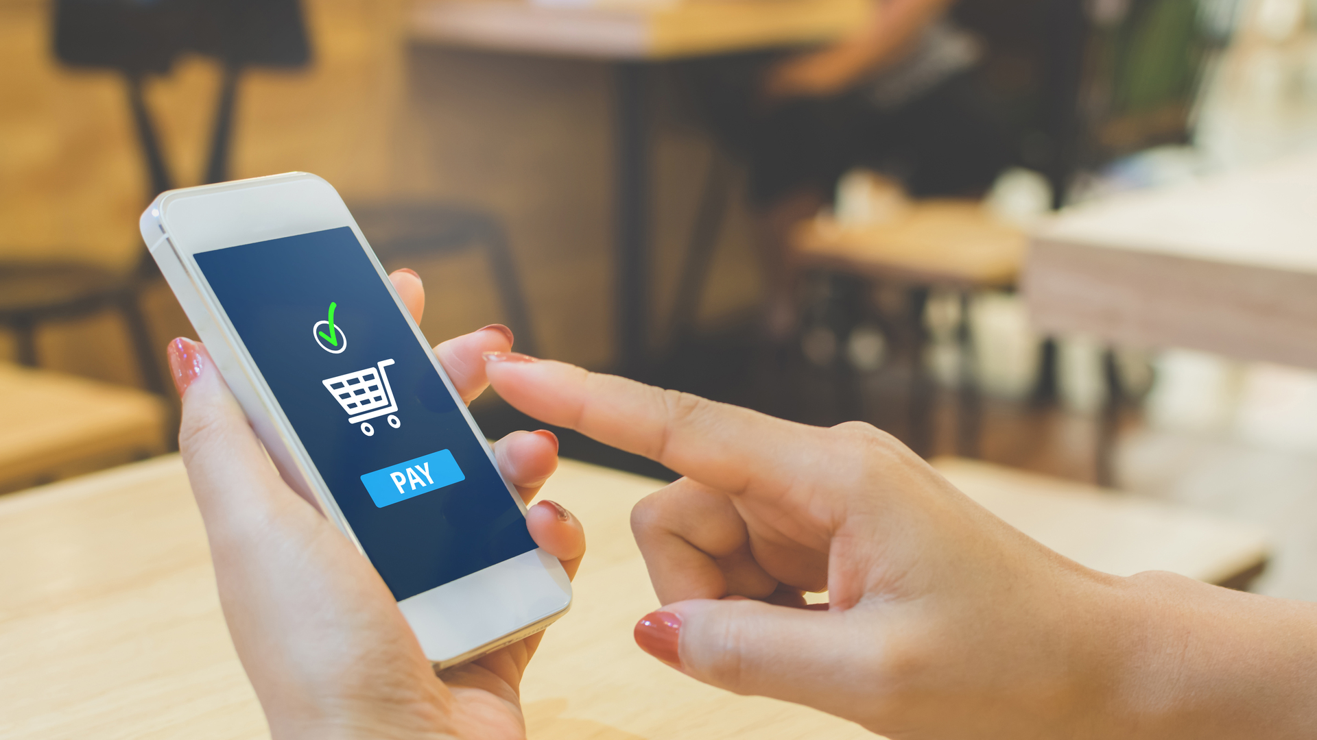 Concept online payment mobile technology. Hand of female using smartphone touching pay button mobile banking application in restaurant