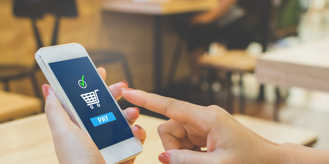 Concept online payment mobile technology. Hand of female using smartphone touching pay button mobile banking application in restaurant