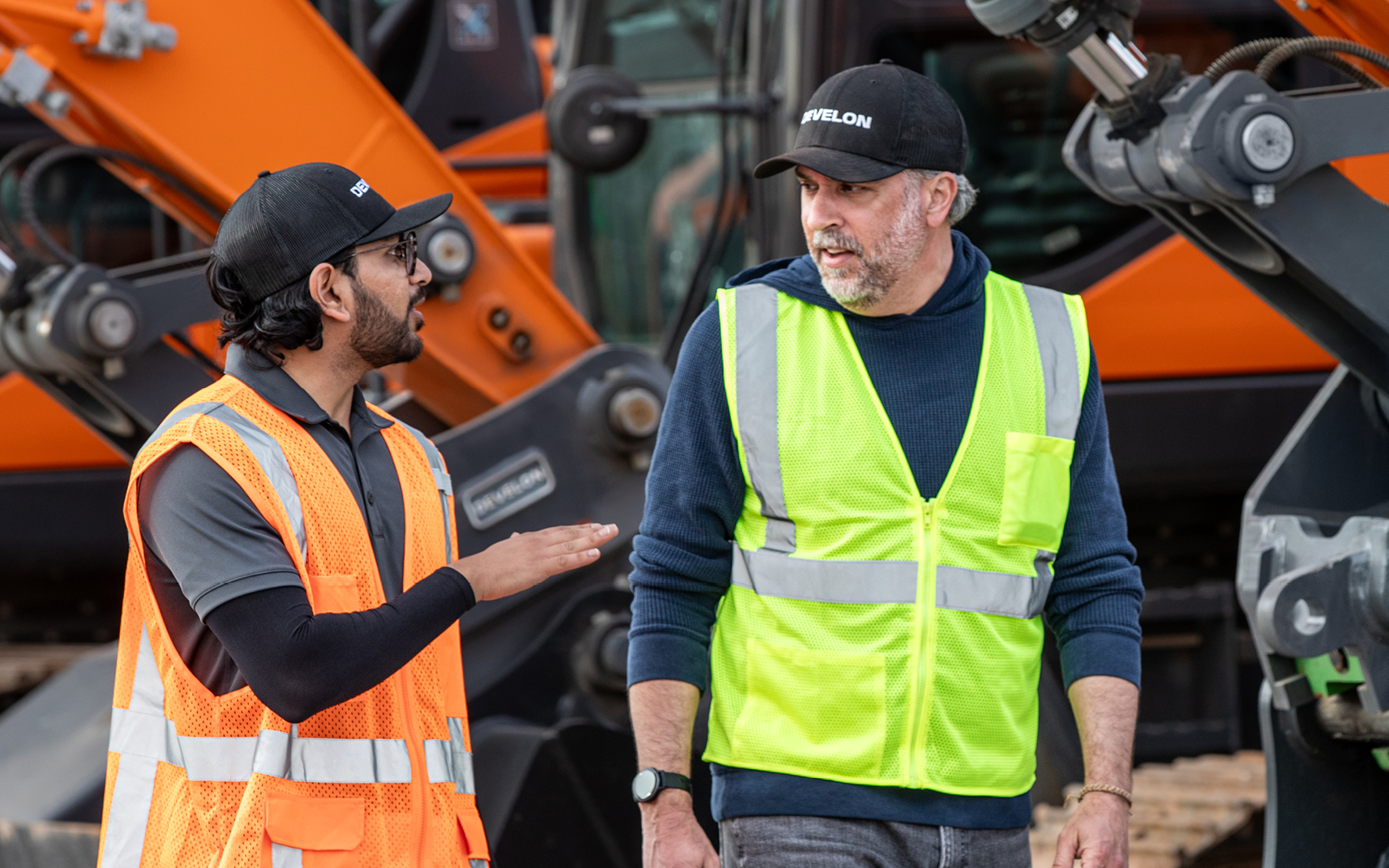 A dealership employee visits with a heavy construction equipment operator at a jobsite.