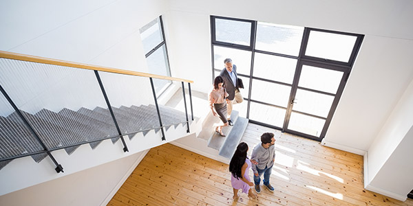 Four adults, dressed in business casual wear, walk down a flight of stairs together talking  