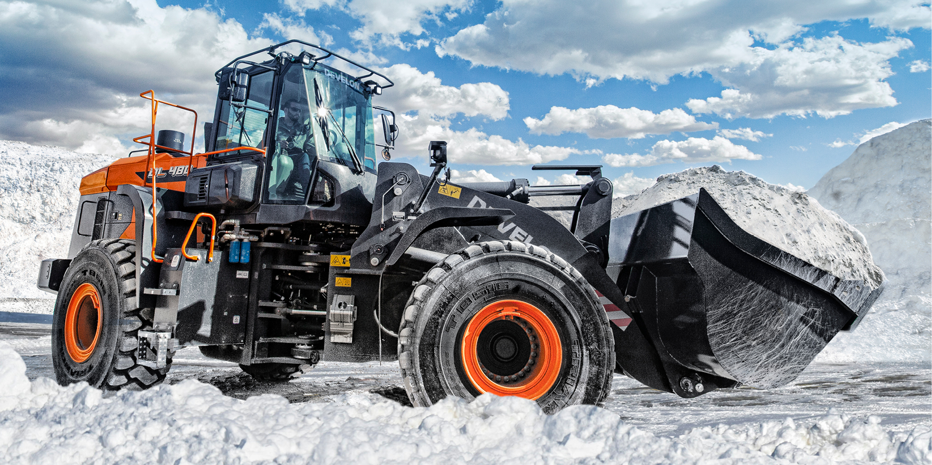 A DEVELON wheel loader hauling a bucket of snow. 