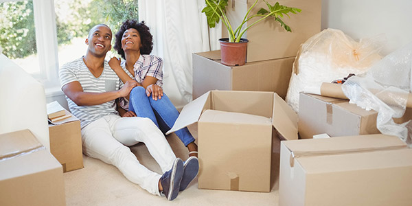 couple sitting down the floor sorrounded by moving boxes