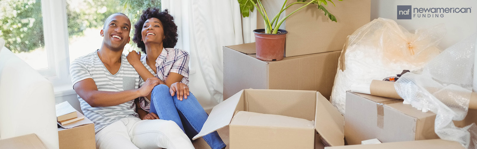 couple sitting down the floor sorrounded by moving boxes