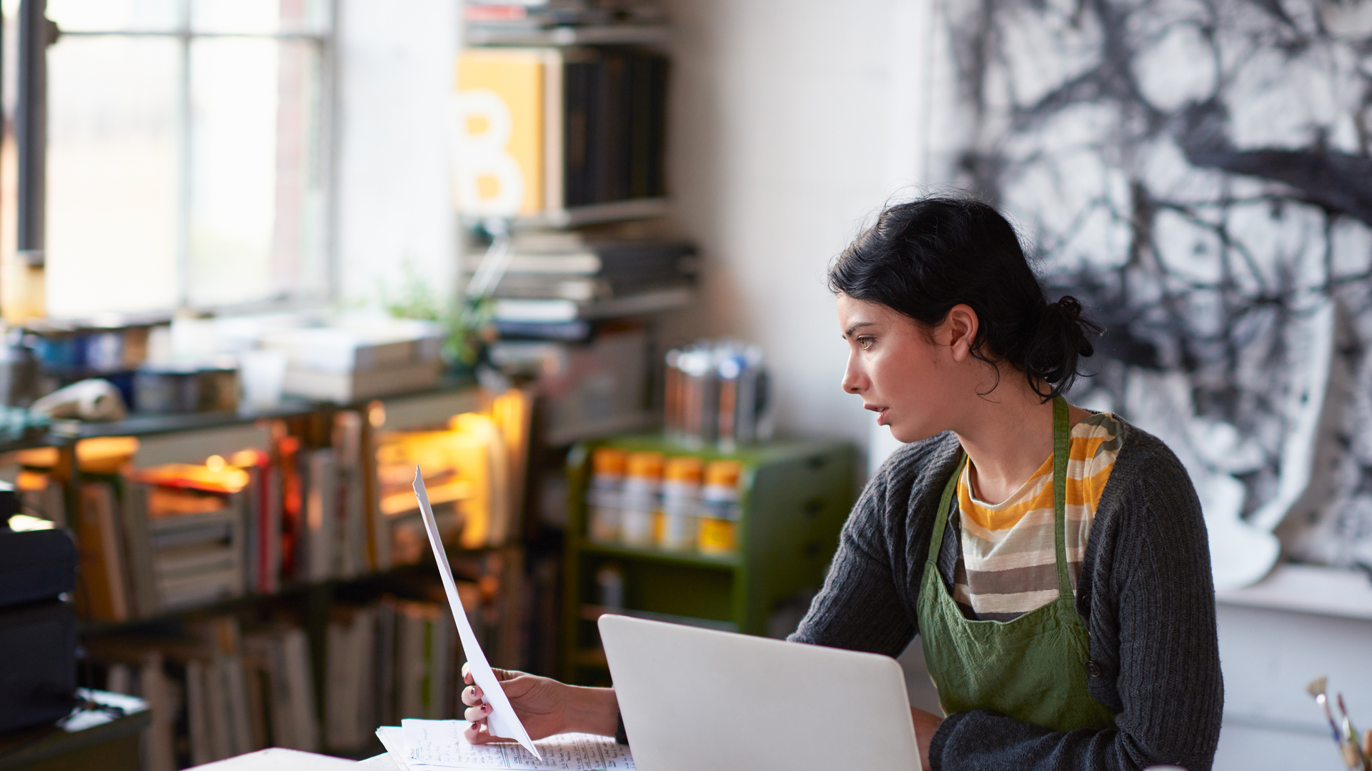 Young female artist in studio working on laptop