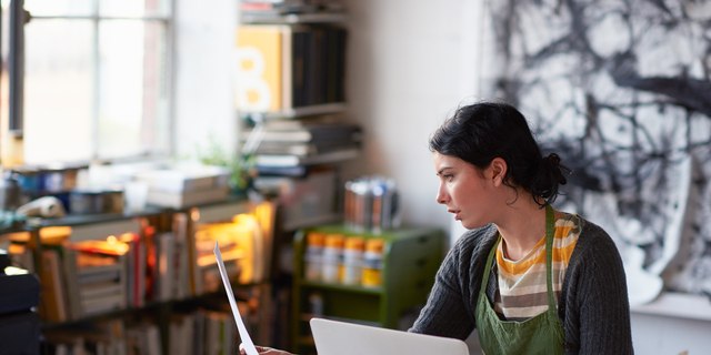 Young female artist in studio working on laptop