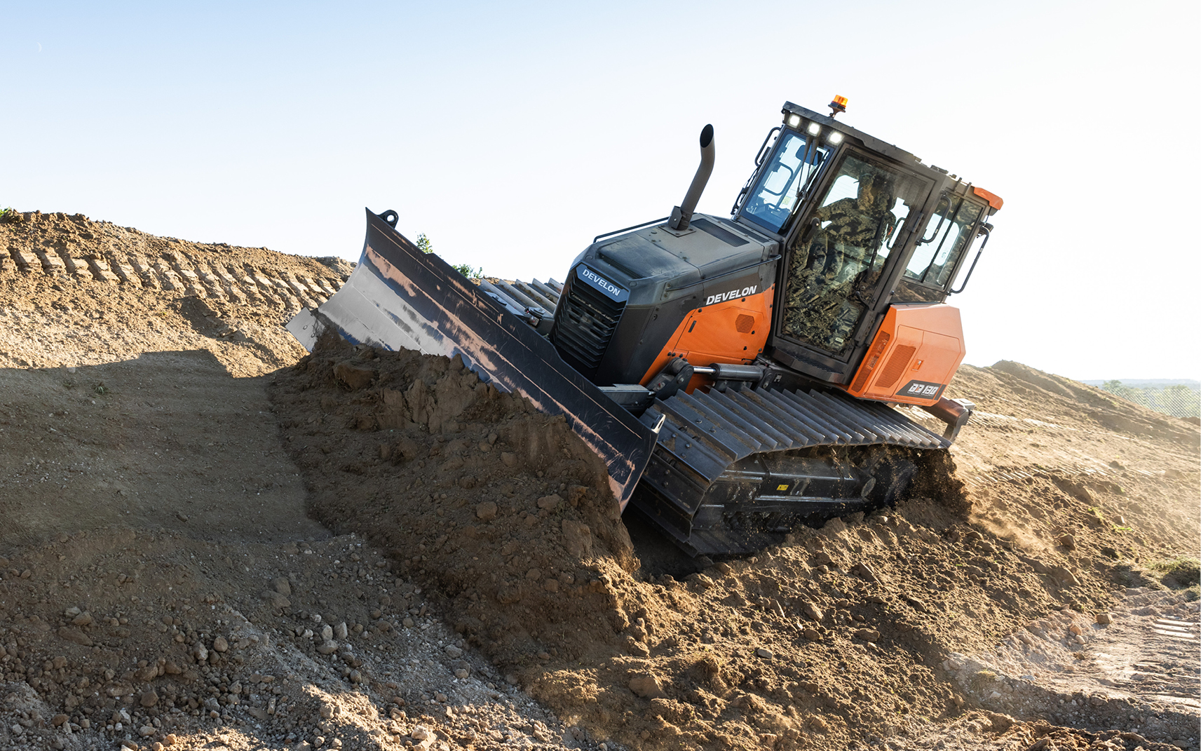 DEVELON compact track loader pushing dirt on a construction site.