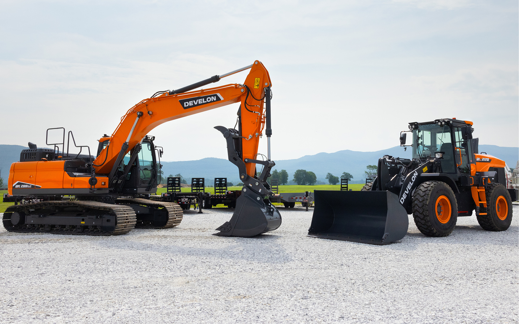 A DEVELON crawler excavator and wheel loader parked in a heavy equipment dealer lot. 