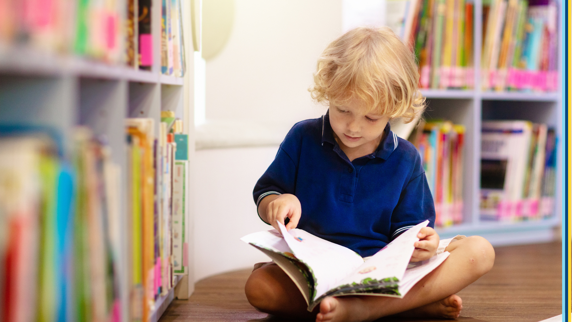 Young child sitting in a library reading a picture book.
