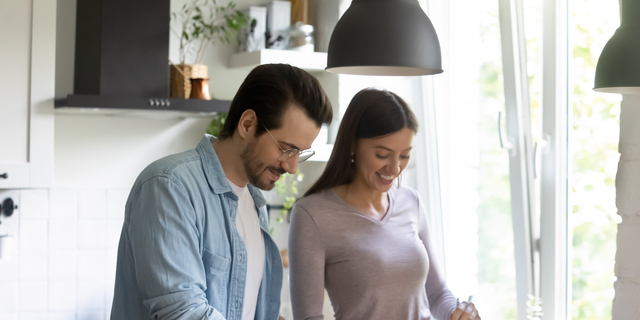 Happy millennial couple cook healthy salad in kitchen